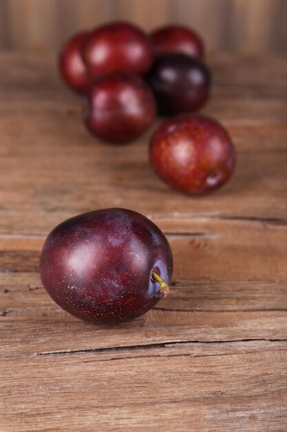 Ripe plums on wooden table closeup