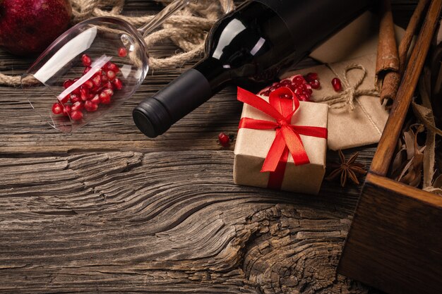 Ripe pomegranate fruit with a glass of wine, a bottle and a gift