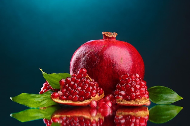 Ripe pomegranate fruit with leaves on blue background