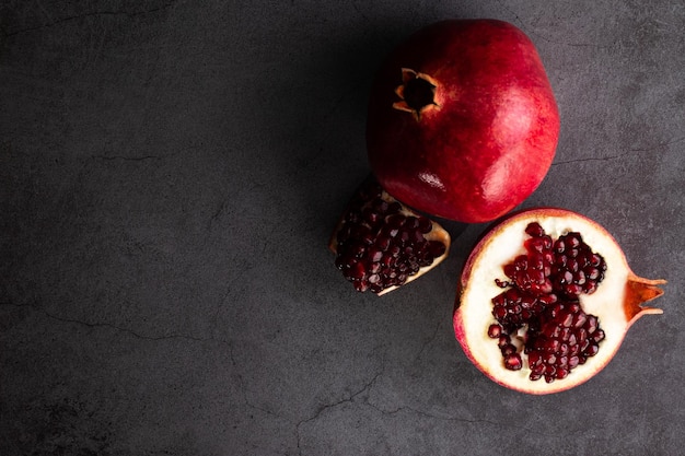 Ripe pomegranate fruits on a dark background, top view with copy space.