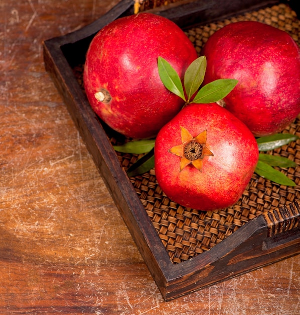 Ripe pomegranate fruits on the wooden background. Top view.