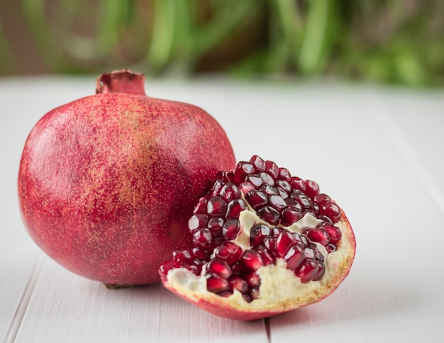 Ripe pomegranate seeds on a white wooden table