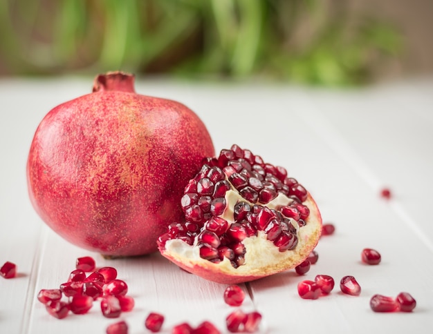 Ripe pomegranate seeds on a white wooden table