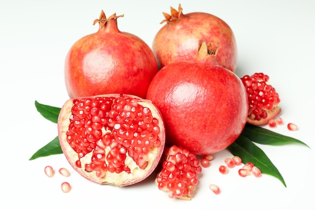 Ripe pomegranate with leaves on white background