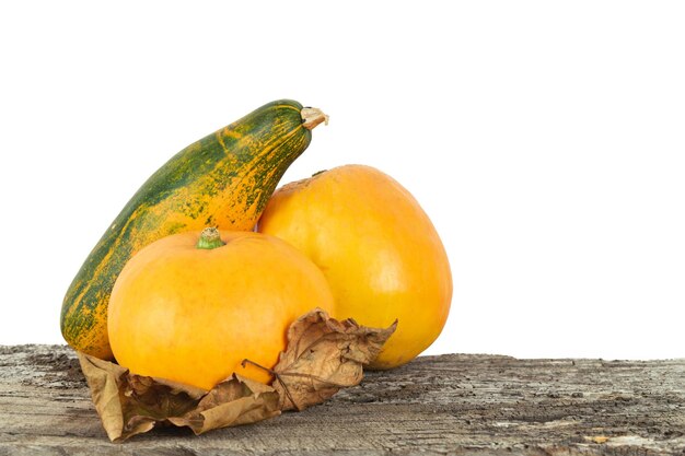 Ripe pumpkins of various shapes on wooden background with dried leaves Png file