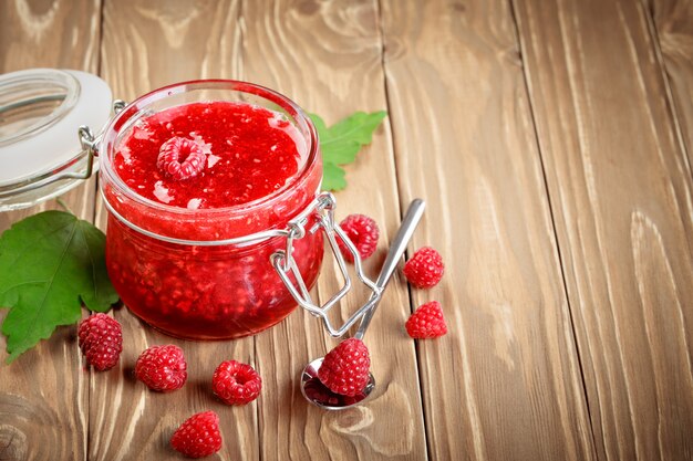 Ripe raspberry and raspberry jam on a wooden table.