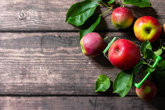 Ripe red apples in shopping cart on wooden background Top view flat lay background Copy space