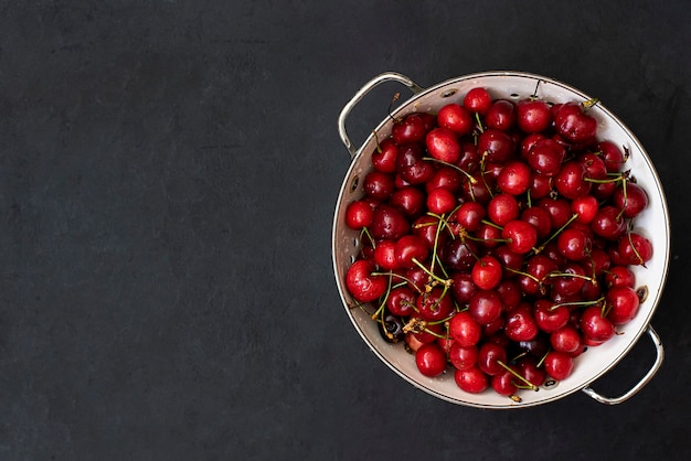 Ripe red cherries in a white colander