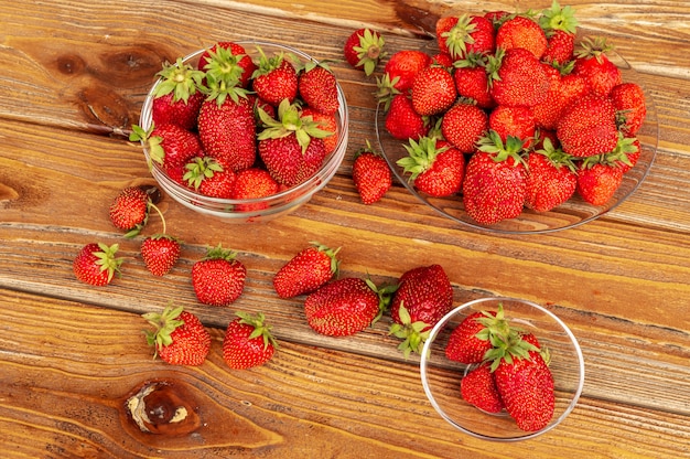 Ripe red organic strawberries against brown wooden background.