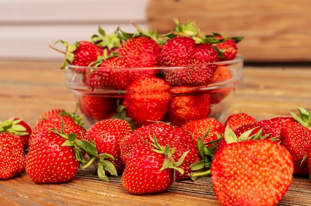 Ripe red organic strawberries against brown wooden background.