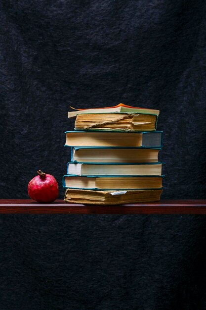 Ripe red pomegranate with books on the shelf