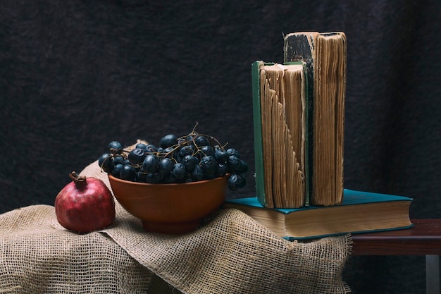 Ripe red pomegranates grapes and books on the table