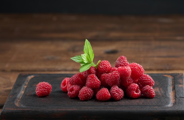 Ripe red raspberries on a brown wooden board