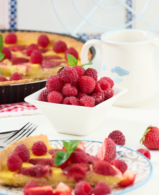 Ripe red raspberries in a white ceramic bowl