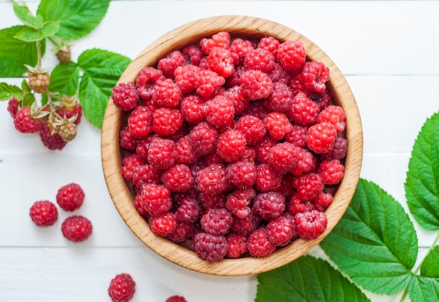 Ripe red raspberries in a wooden bowl 