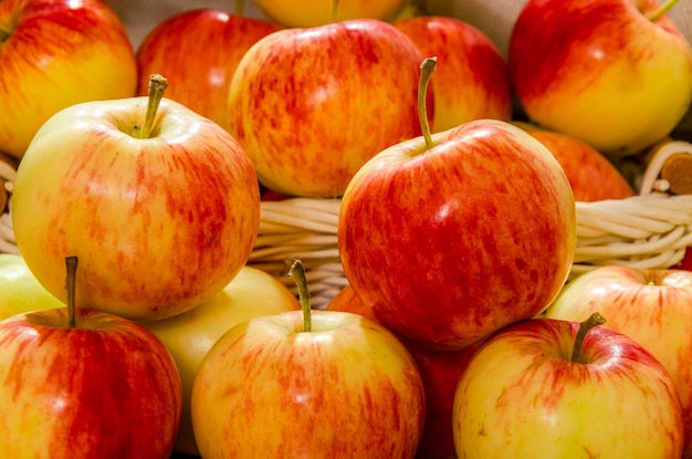 Ripe red and yellow apples in a basket on the table.