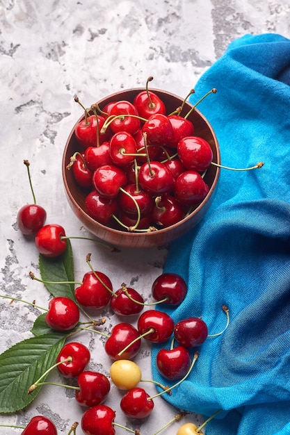 Ripe red and yellow cherries in bowl on gray background