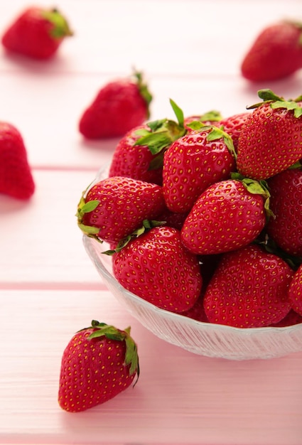 Ripe strawberries in glass bowl on pink background