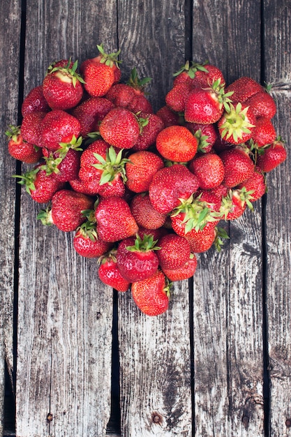 Ripe strawberries heart on wood