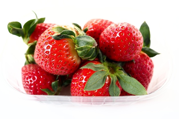 Ripe strawberries in a plastic package on a white background Delicious fresh berries in a container for sale to customers Keeping food fresh Healthy food vitamins and microelements