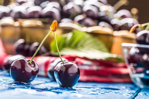 Ripe sweet cherries on blue woden table with water drops.