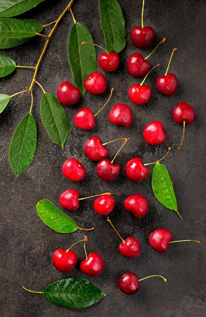 Ripe sweet cherry berry with leaves on a black wooden