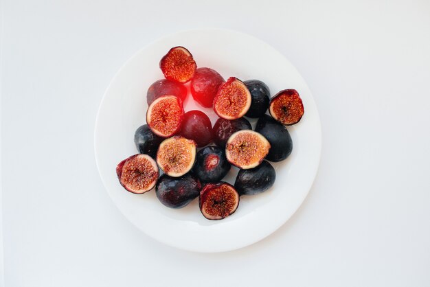 Ripe and sweet figs cut and arranged in a plate on a white background with free space. Fruits and vegetarianism.