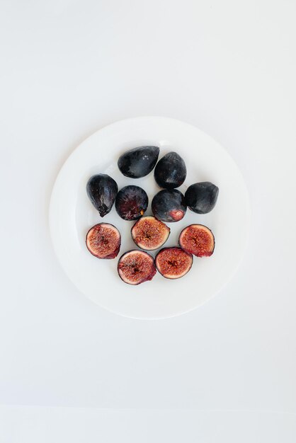 Ripe and sweet figs cut and arranged in a plate on a white background with free space. Fruits and vegetarianism.