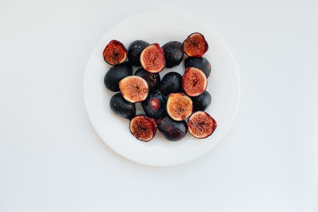 Ripe and sweet figs cut and arranged in a plate on a white surface with free space