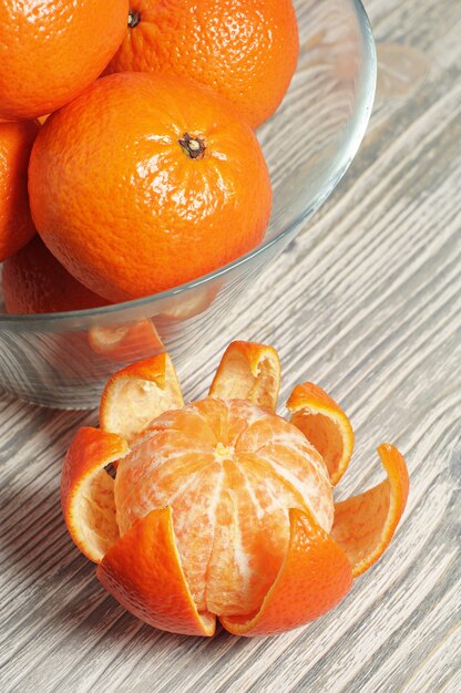 Ripe tangerines in glass bowl on rustic wooden table