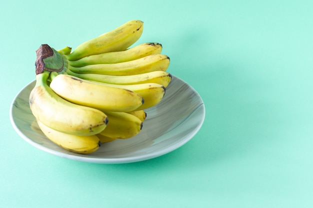 Ripe tasty banans on a plate on blue background. Healty eating concept.