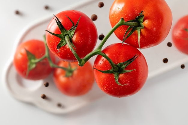 Ripe tomatoes on a branch, white background, top view, close-up