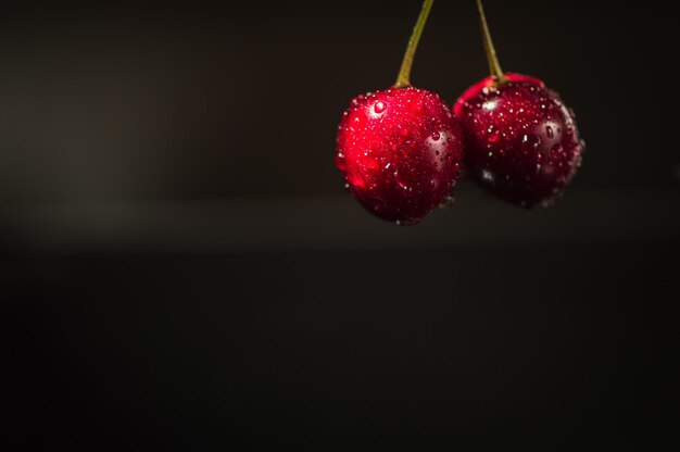 Ripe wet sweet cherries are poured out of the blue bowl on wooden background