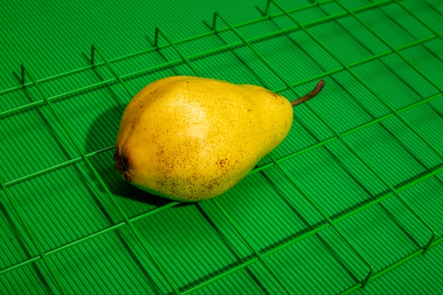 Ripe yellow pear on a grid on a green background