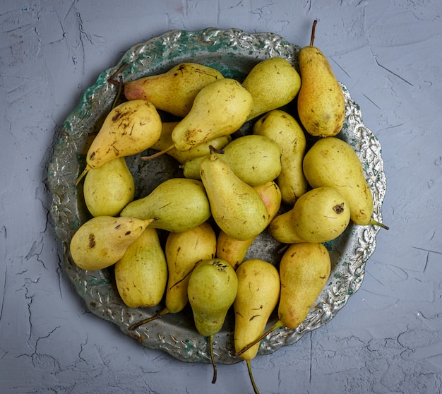 Ripe yellow pears in a round iron plate