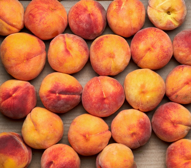 Ripe yellow-red round peaches lie in a row