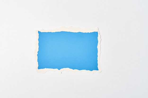 Ripped blue paper torn edge sheet on white background. Template with piece of color paper