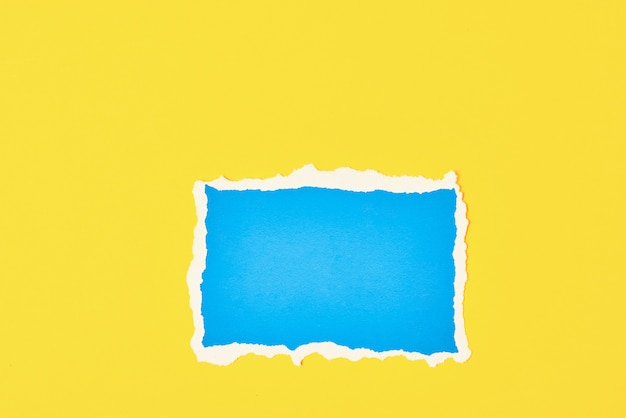 Ripped blue paper torn edge sheet on yellow background