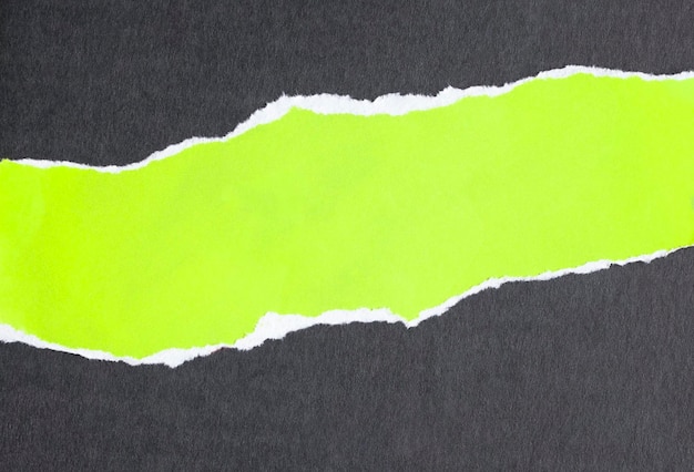 Ripped fluorescent green paper on black background