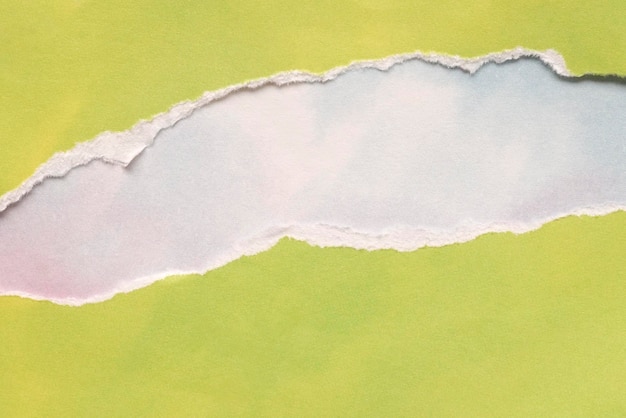 Ripped lemon green paper on blue white sky background