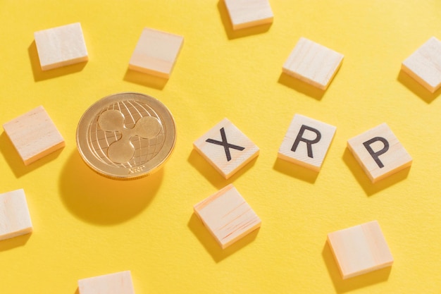 Ripple coin, the name of the cryptocurrency in wooden letters on a yellow background with hard shadows in close-up