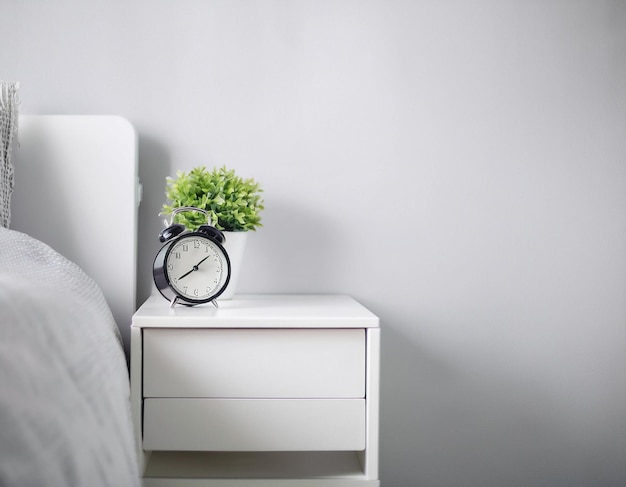 Photo rise and shine good morning concept with alarm clock and houseplant on bedside table