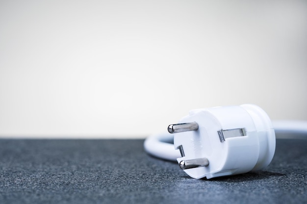 Rising electricity costs Electric cable with plug on grey background with copy space selective focus