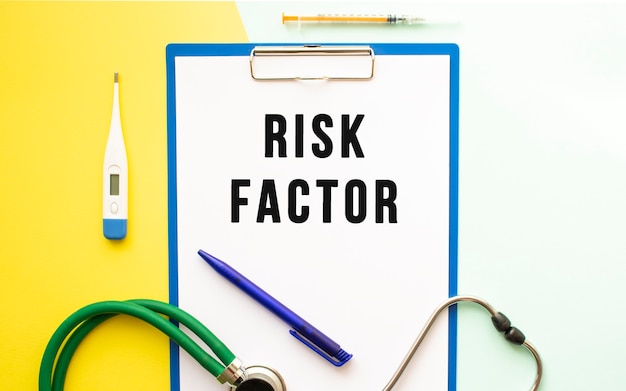 RISK FACTORS text on a letterhead in a medical folder on a beautiful background. Stethoscope, thermometer and pen.