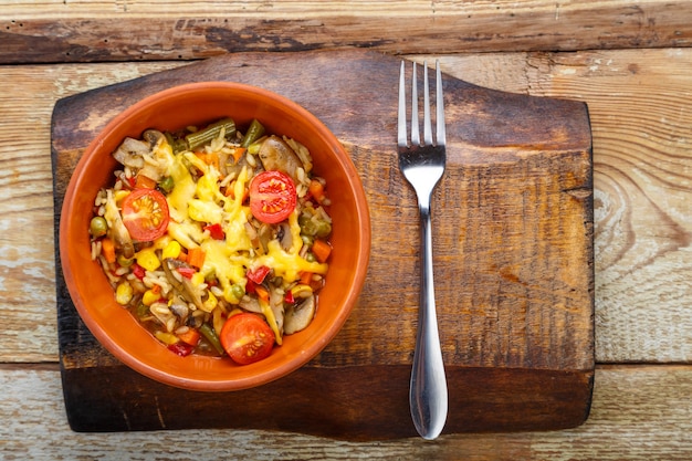 Risotto with mushrooms in a plate on a wooden background on a wooden stand next to a fork.