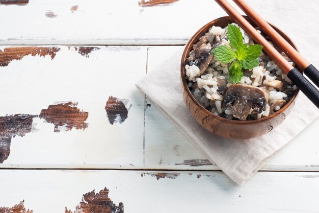 Risotto with mushrooms on a wooden bowl and chopsticks