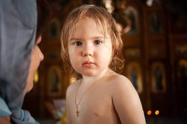 The ritual of baptism. A beautiful Christian church painted on the walls icons. a baptised two-year-old looks into the camera, a portrait.