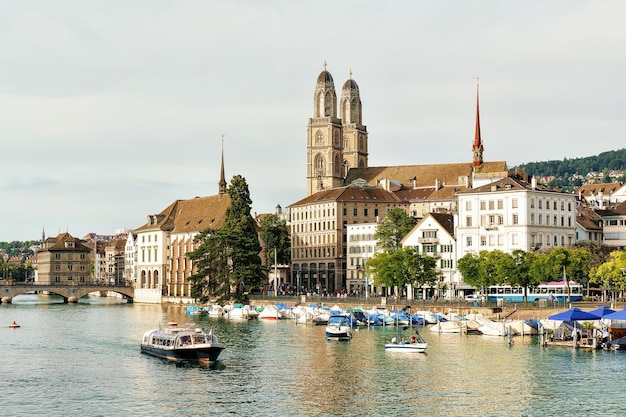 River boat at Limmat Quay and Grossmunster Church in Zurich, Switzerland. People on the background