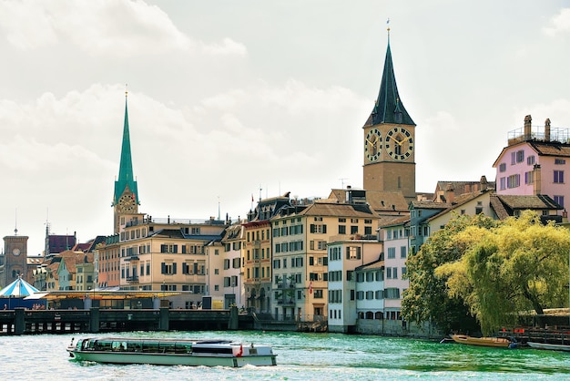 River cruiser at Limmat quay and Saint Peter Church and Fraumunster Church in the city center of Zurich, Switzerland.