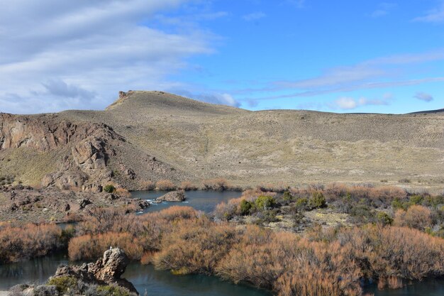 a river runs through a rocky landscape with a mountain in the background